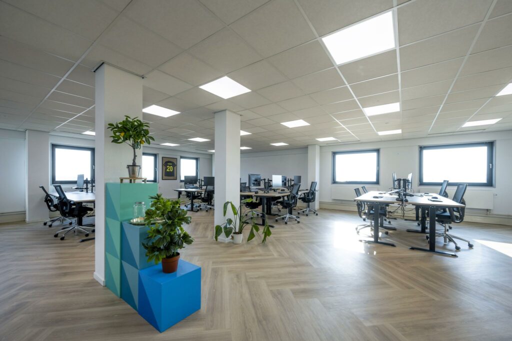 Licht en modern kantoor aan de Joan Muyskenweg met flexwerkplekken, planten en grote ramen.